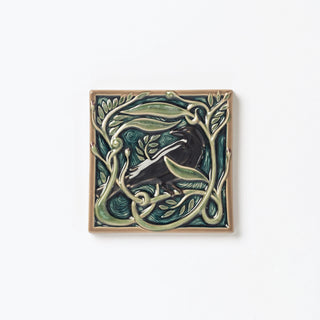 Decorative ceramic tile with Rook or Crow in center surrounded by leaves.