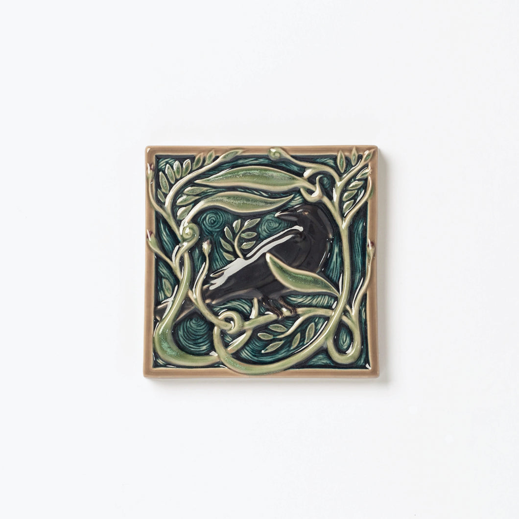 Decorative ceramic tile with Rook or Crow in center surrounded by leaves.